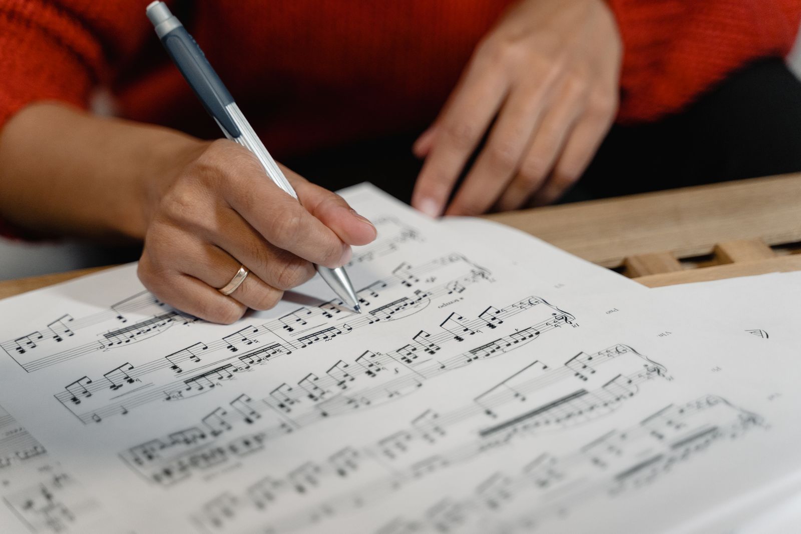 En hånd skriver noder på nodepapir. Genrefoto om musikskabelse.