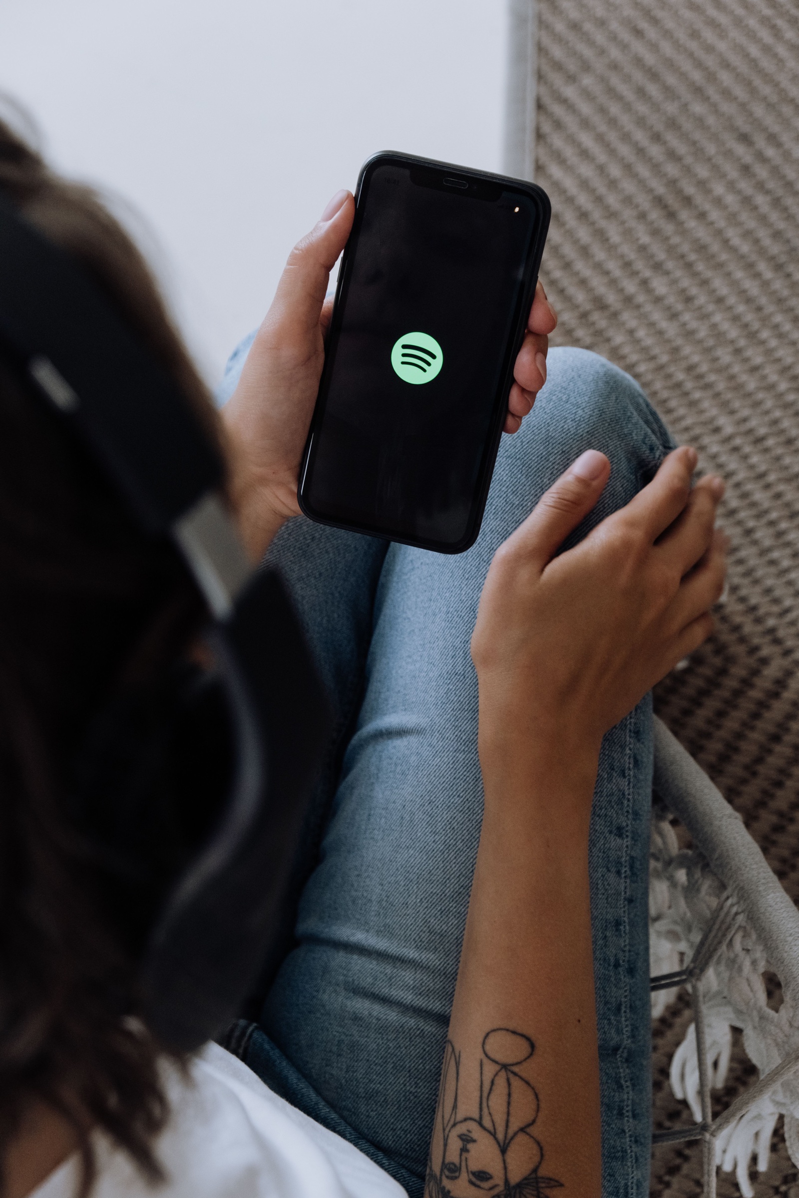 En person med hovedtelefoner holder en telefon med Spotify åbent.
