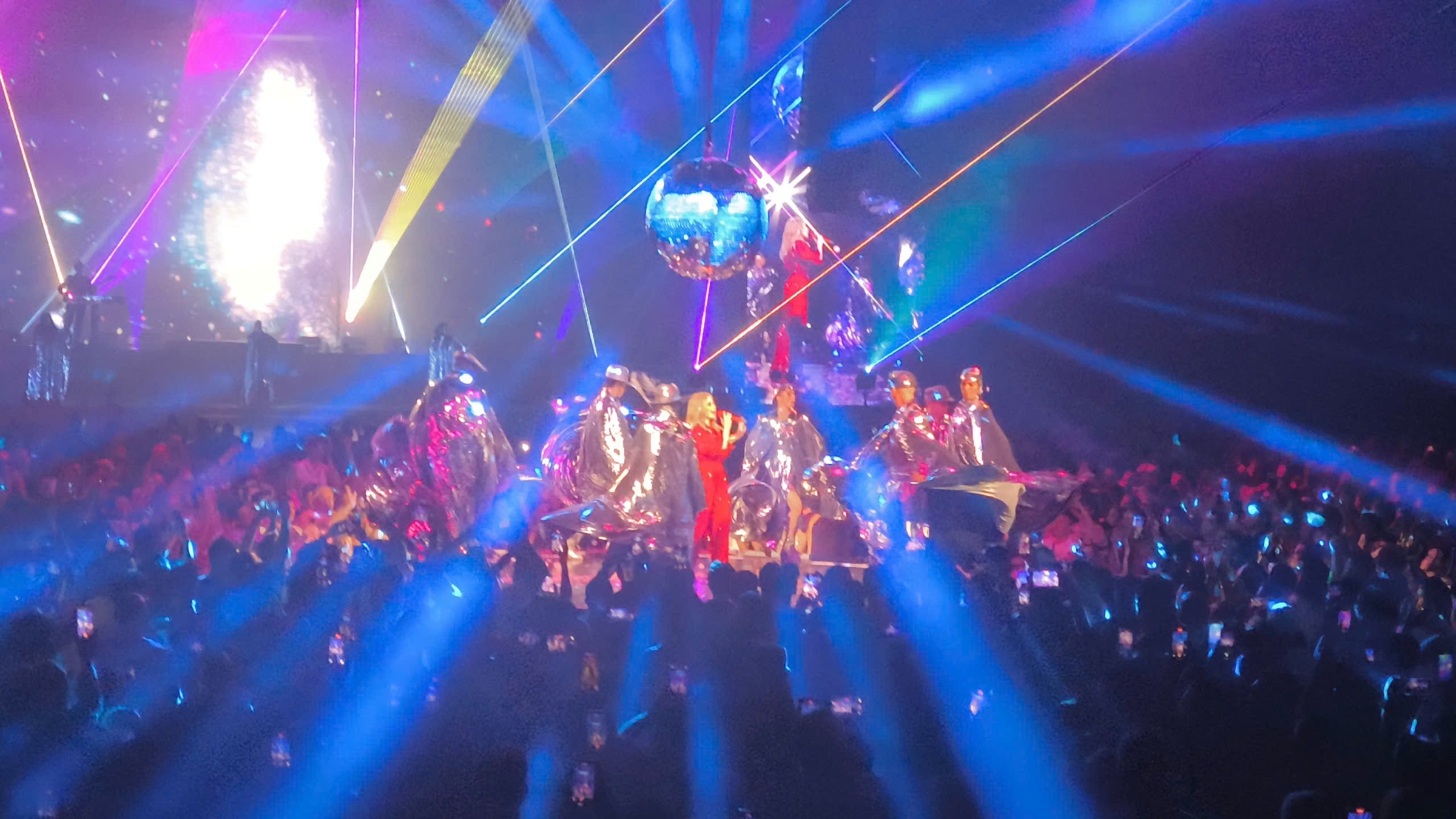 Kylie Minogue optræder på en stor livescene med dansere, scenelys og publikum.